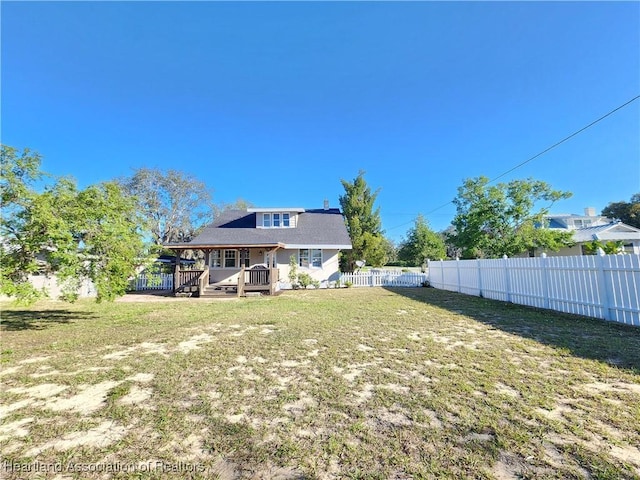 rear view of house with a deck, a lawn, and a fenced backyard