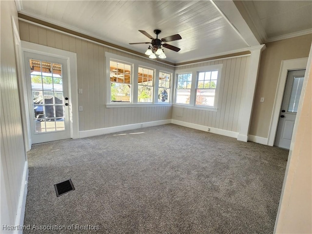 unfurnished room featuring a wealth of natural light, visible vents, carpet flooring, and crown molding