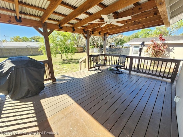 deck with a ceiling fan, a fenced backyard, a lawn, and grilling area