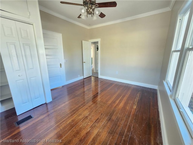 unfurnished bedroom featuring visible vents, baseboards, dark wood finished floors, ornamental molding, and a closet