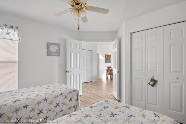 bedroom with light wood-style floors, ceiling fan, and a closet