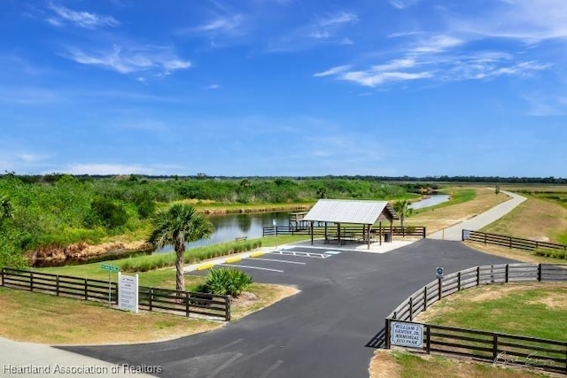 view of home's community featuring fence, a water view, and uncovered parking