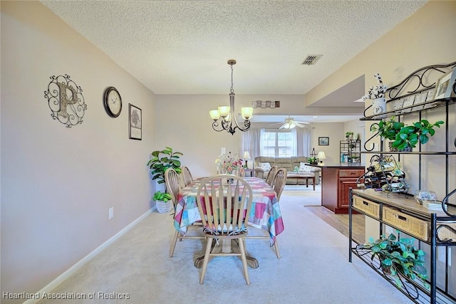 dining room with ceiling fan with notable chandelier, a textured ceiling, and light carpet