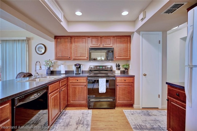 kitchen with black appliances, sink, and light hardwood / wood-style flooring