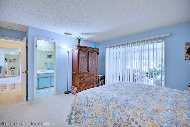 carpeted bedroom with a textured ceiling and ensuite bath