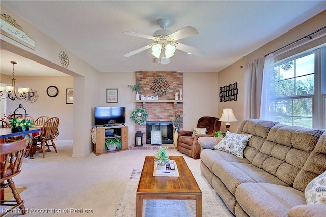 carpeted living room featuring ceiling fan with notable chandelier and a brick fireplace