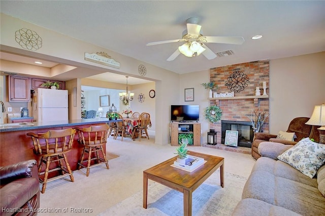 living room with ceiling fan with notable chandelier, light colored carpet, and a fireplace