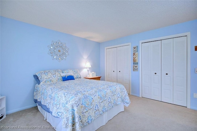 carpeted bedroom featuring a textured ceiling and two closets