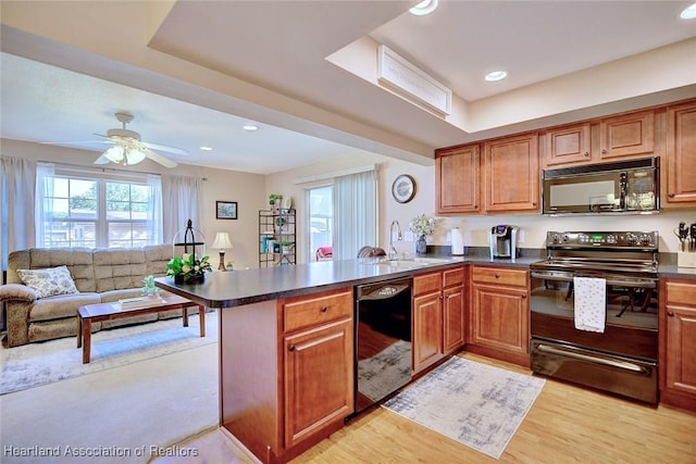 kitchen with black appliances, a healthy amount of sunlight, light wood-type flooring, and kitchen peninsula