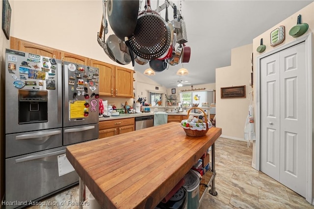 kitchen featuring stainless steel appliances, vaulted ceiling, a sink, wood counters, and a peninsula