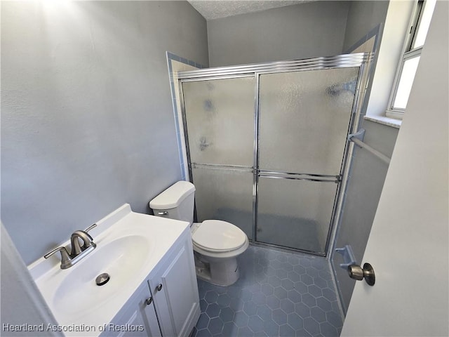 bathroom with tile patterned floors, walk in shower, vanity, a textured ceiling, and toilet