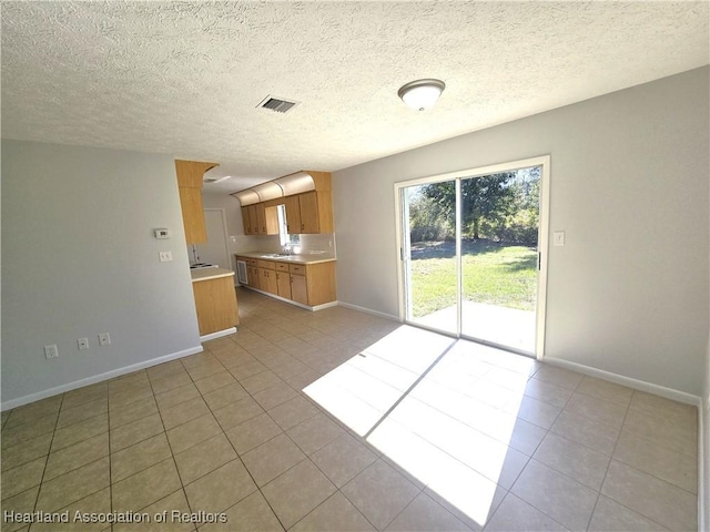 unfurnished living room with sink, light tile patterned floors, and a textured ceiling