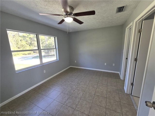 spare room featuring ceiling fan, tile patterned flooring, and a textured ceiling