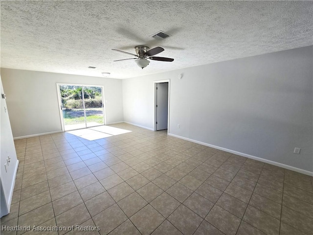 empty room featuring ceiling fan, light tile patterned flooring, and a textured ceiling