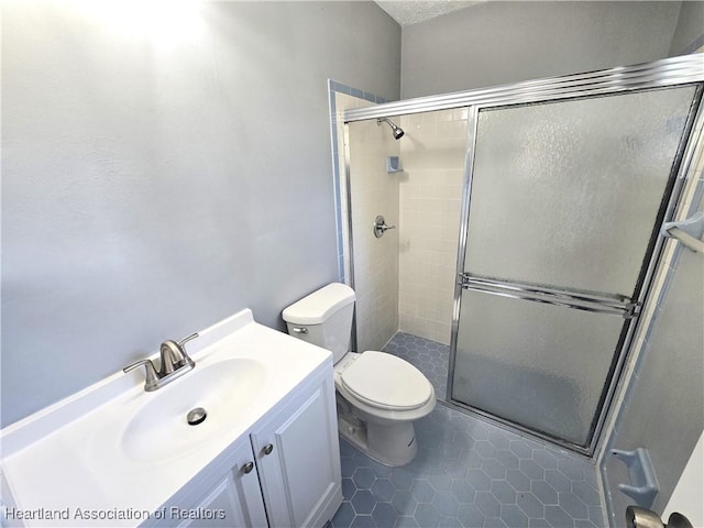 bathroom with tile patterned floors, vanity, toilet, and walk in shower