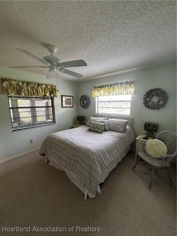 carpeted bedroom with ceiling fan, a textured ceiling, and baseboards