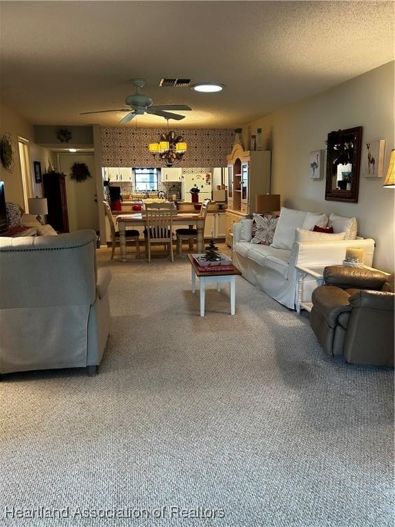 carpeted living room with ceiling fan, a textured ceiling, and visible vents