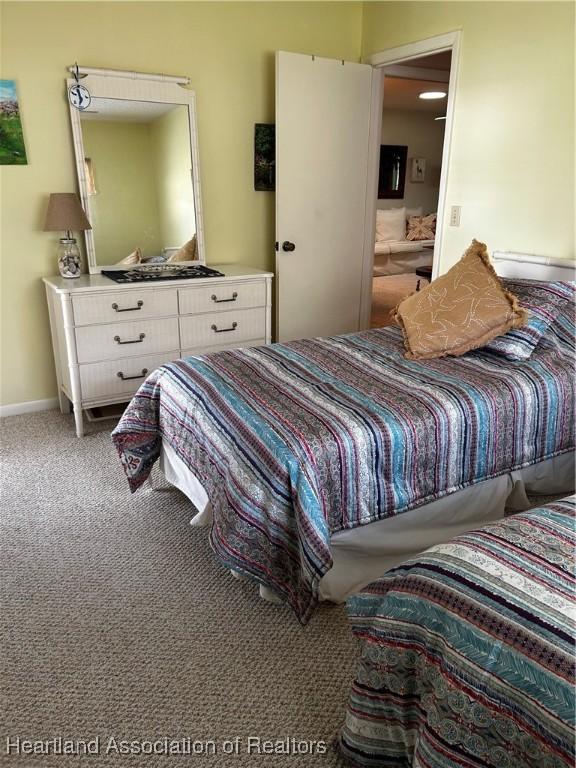 carpeted bedroom featuring ensuite bath and baseboards