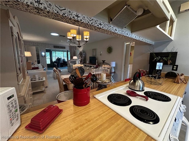 kitchen featuring visible vents, wood finished floors, hanging light fixtures, an inviting chandelier, and white electric range