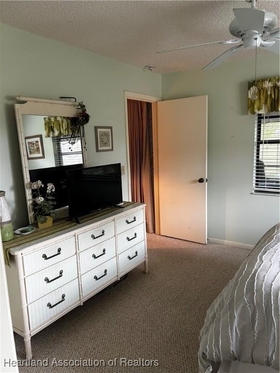 bedroom featuring dark colored carpet, ceiling fan, and a textured ceiling