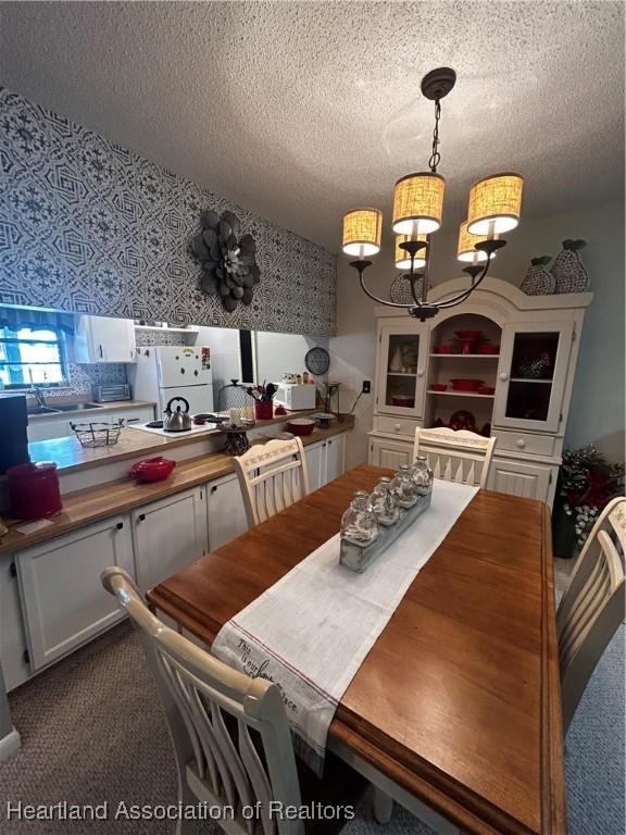 dining area featuring a textured ceiling, wallpapered walls, and a notable chandelier