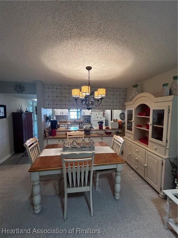 dining area featuring light carpet, a notable chandelier, a textured ceiling, and wallpapered walls