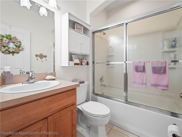 bathroom featuring tile patterned floors, vanity, toilet, and bath / shower combo with glass door