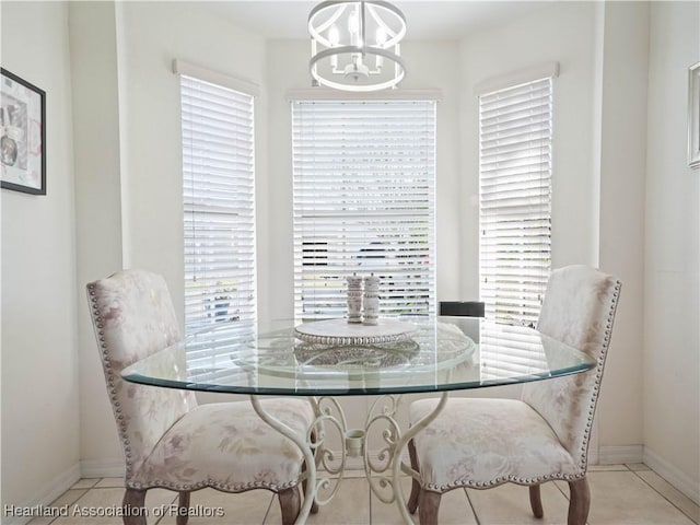 dining area with baseboards, tile patterned floors, a wealth of natural light, and an inviting chandelier