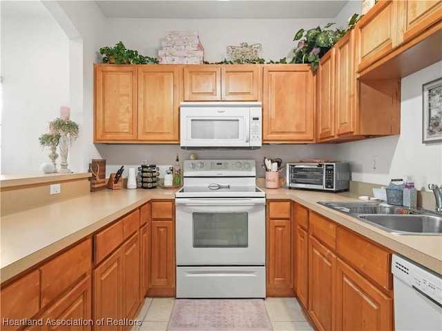 kitchen featuring white appliances, light countertops, a sink, and light tile patterned flooring