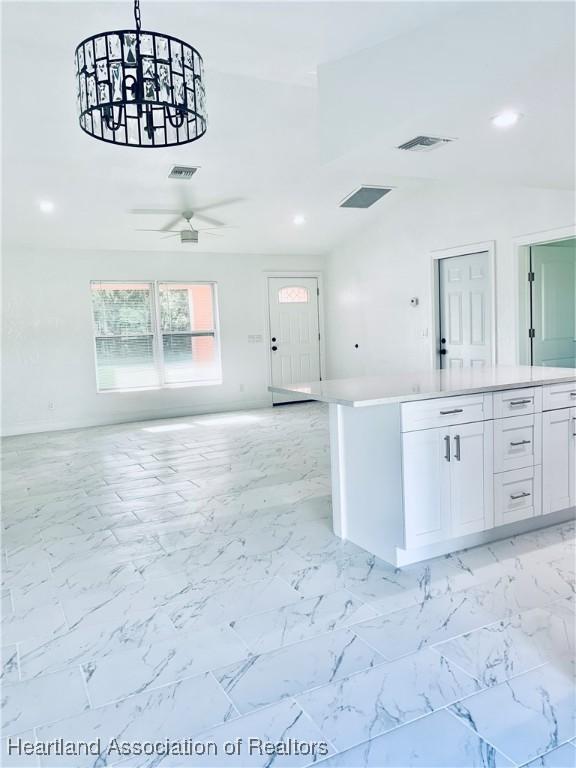 kitchen featuring ceiling fan, white cabinetry, and hanging light fixtures