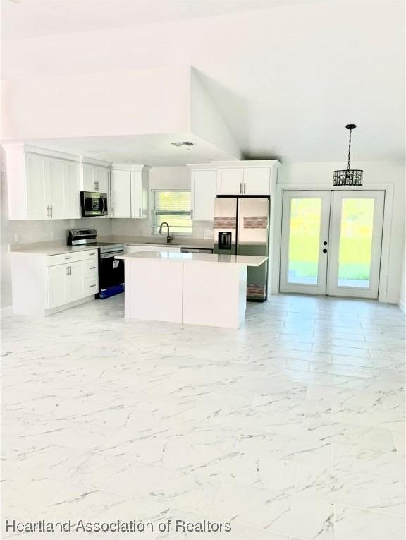 kitchen with white cabinetry, a center island, sink, stainless steel appliances, and pendant lighting