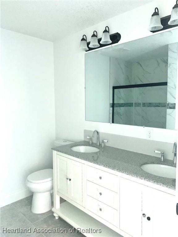 bathroom featuring tile patterned floors, vanity, toilet, and a shower with door