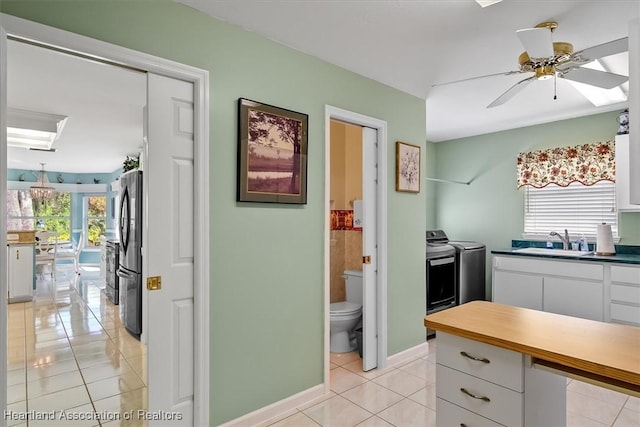 3243 E Anglers Strm, Avon Park, FL 33825 - kitchen featuring freestanding refrigerator, light tile patterned floors, washer and dryer, white cabinets, and ceiling fan