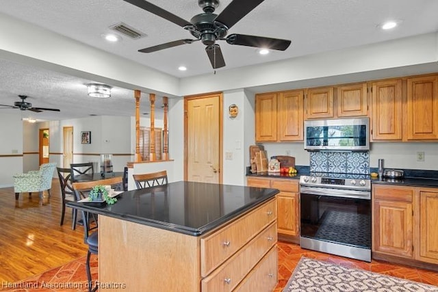 kitchen featuring dark countertops, a breakfast bar area, stainless steel appliances, and a center island