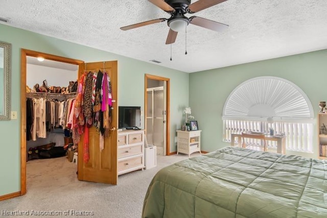 bedroom with visible vents, light colored carpet, a walk in closet, a textured ceiling, and a closet