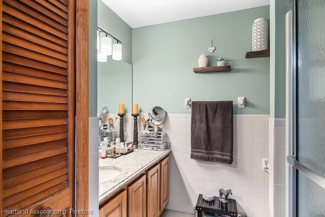 bathroom featuring tile walls, a closet, wainscoting, and vanity