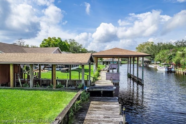 dock area with a water view, boat lift, and a lawn