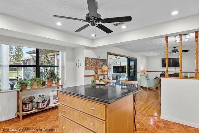 kitchen featuring dark countertops, recessed lighting, open floor plan, a kitchen island, and a textured ceiling