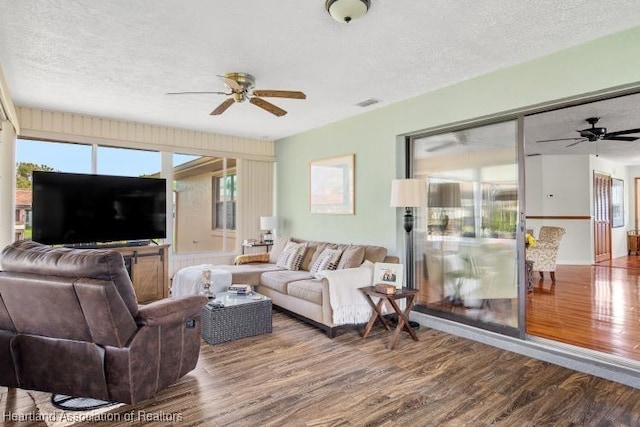 living room featuring a wealth of natural light, a textured ceiling, and wood finished floors