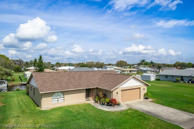 ranch-style home featuring concrete driveway, a front lawn, an attached garage, and a water view