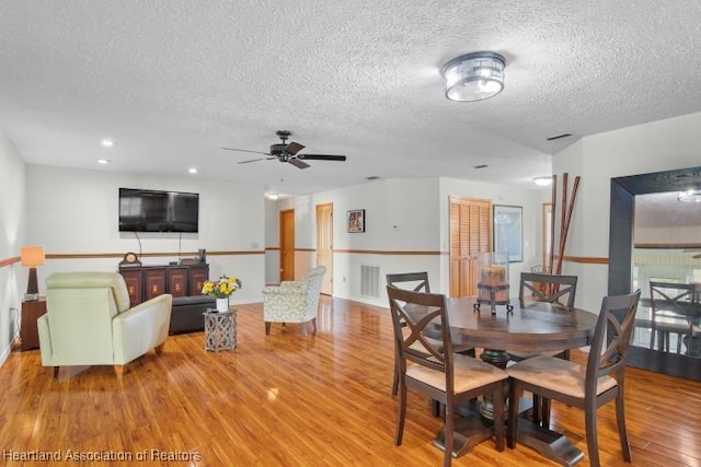 dining room with a ceiling fan, light wood-type flooring, visible vents, and a textured ceiling