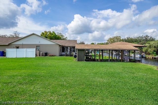 back of property with a water view, a yard, and fence