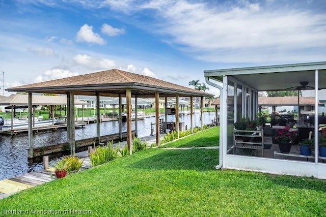 view of dock with a water view and a lawn