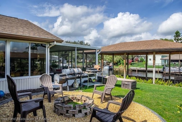 view of patio featuring a sunroom, a water view, and a fire pit