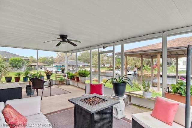 sunroom featuring ceiling fan and a water view