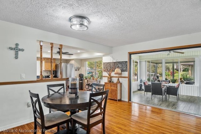 dining space with light wood finished floors, a textured ceiling, baseboards, and a ceiling fan