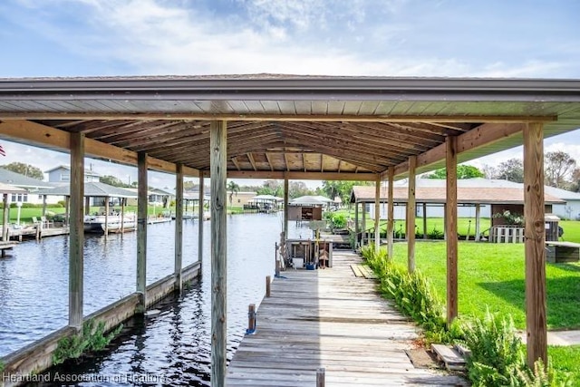 dock area featuring a water view, a lawn, and boat lift