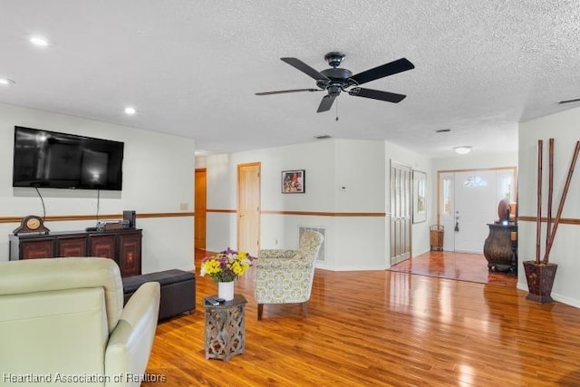 living room with light wood finished floors, baseboards, ceiling fan, a textured ceiling, and recessed lighting