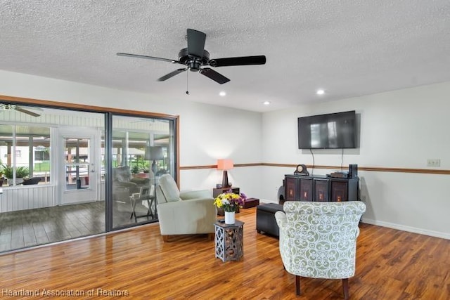 living room featuring baseboards, a ceiling fan, wood finished floors, a textured ceiling, and recessed lighting