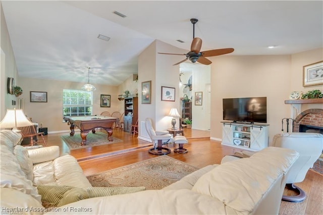 living room with a fireplace, light hardwood / wood-style floors, vaulted ceiling, and pool table